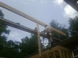 Carpenter setting a ridge beam over a new addition frame — Ice Dam Removal by Roofing Brothers in Springwater