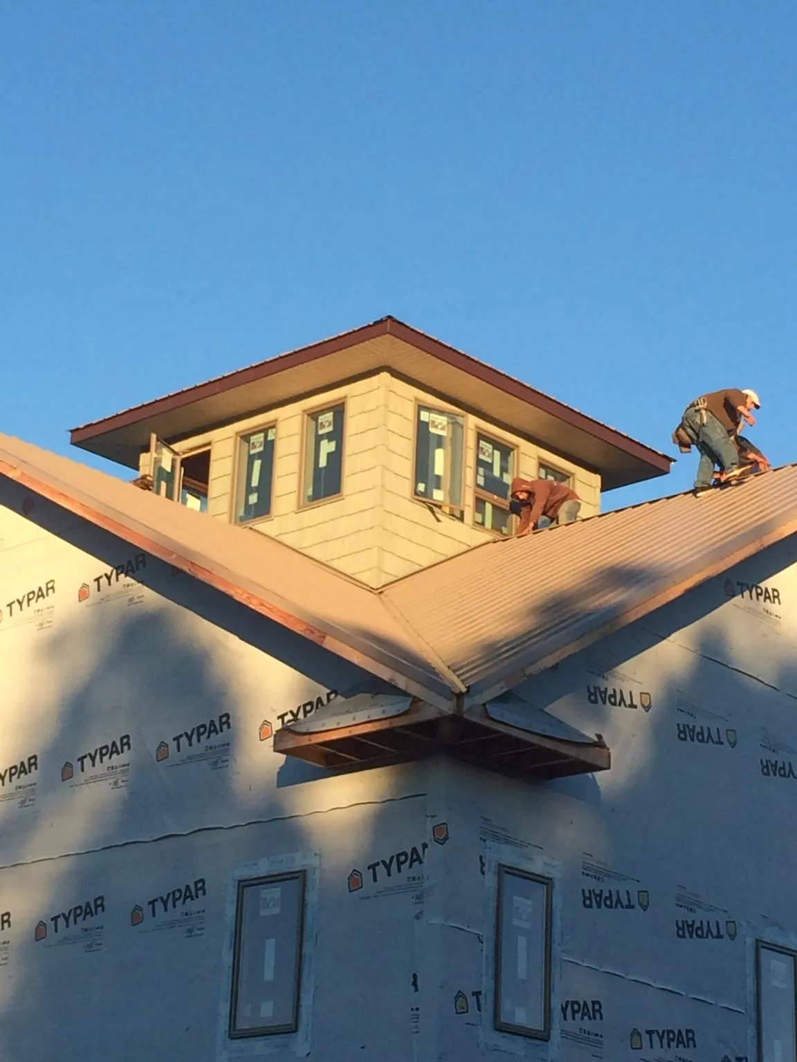 Roofers working around a rooftop cupola on a new metal roof at sunset — Roof Waterproofing in Springwater by Roofing Brothers